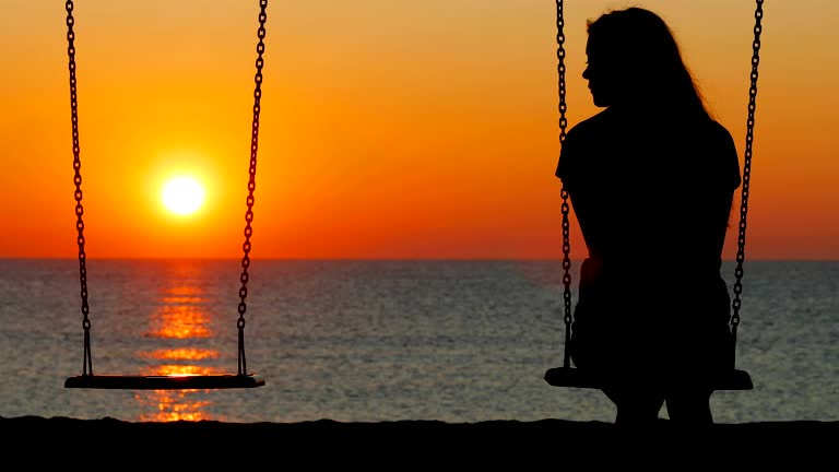 Silhouette Of A Sad Girl Swinging Looking At Side